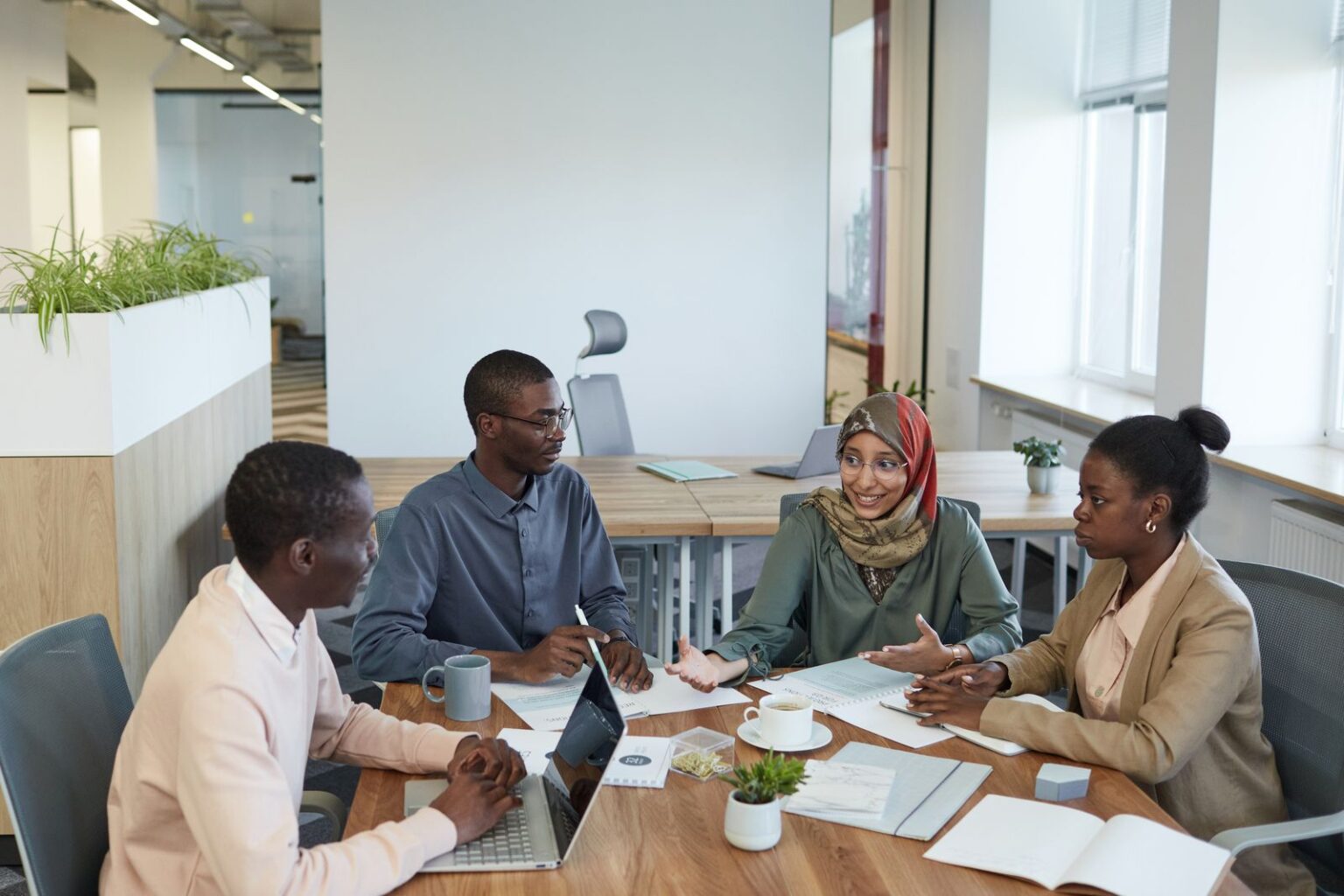 Colleagues in a bright office talking around a meeting table