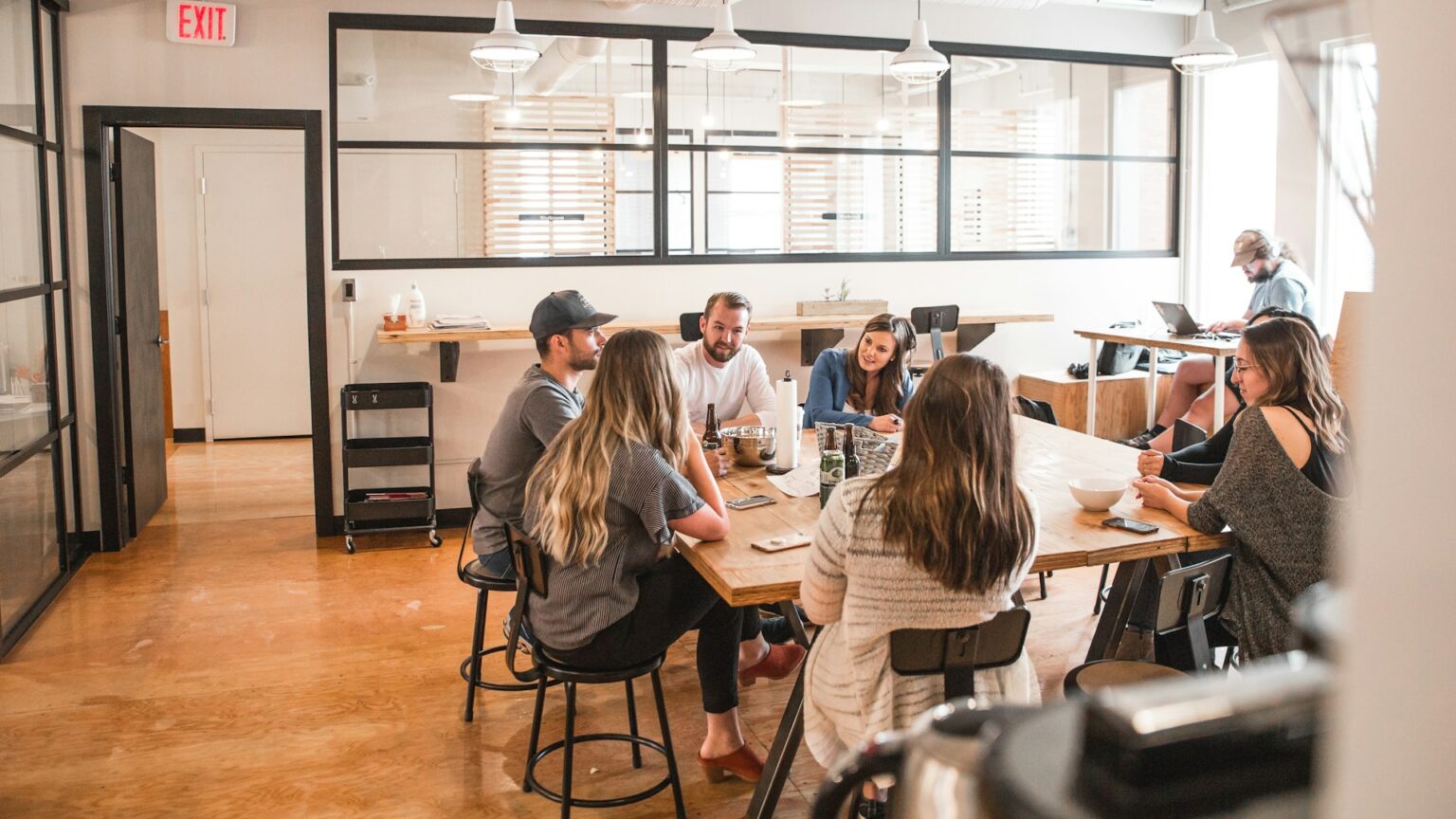 Colleagues talking around a table in a bright open-plan office