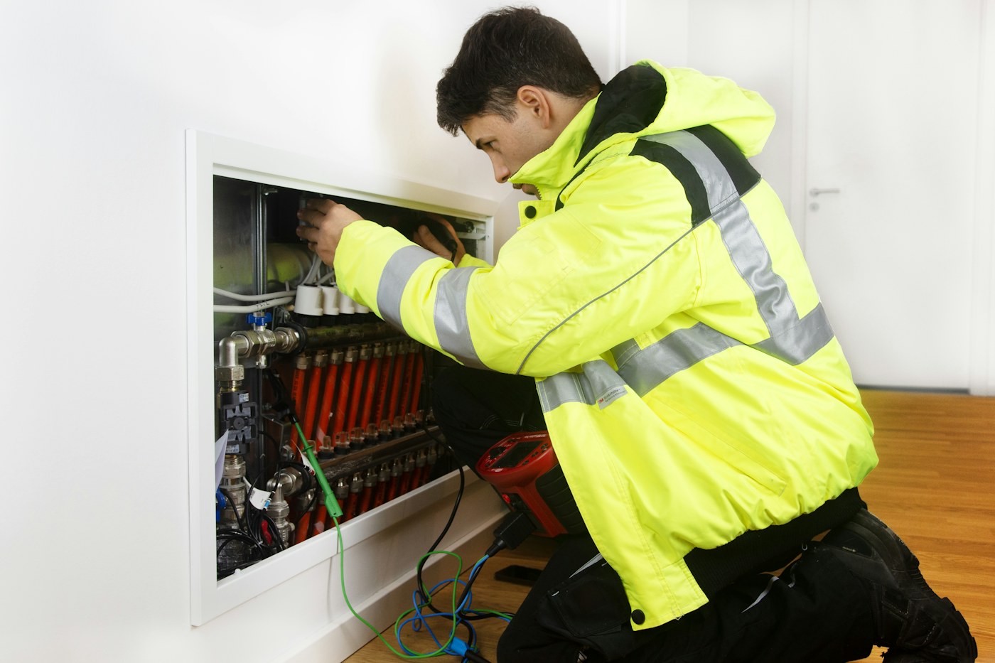 A heating engineer in a hi-vis jacket working on a manifold