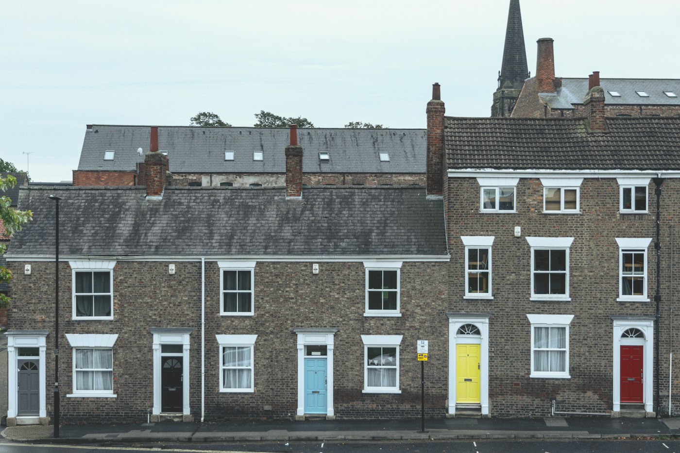 A row of brick terraced houses with brightly painted front doors