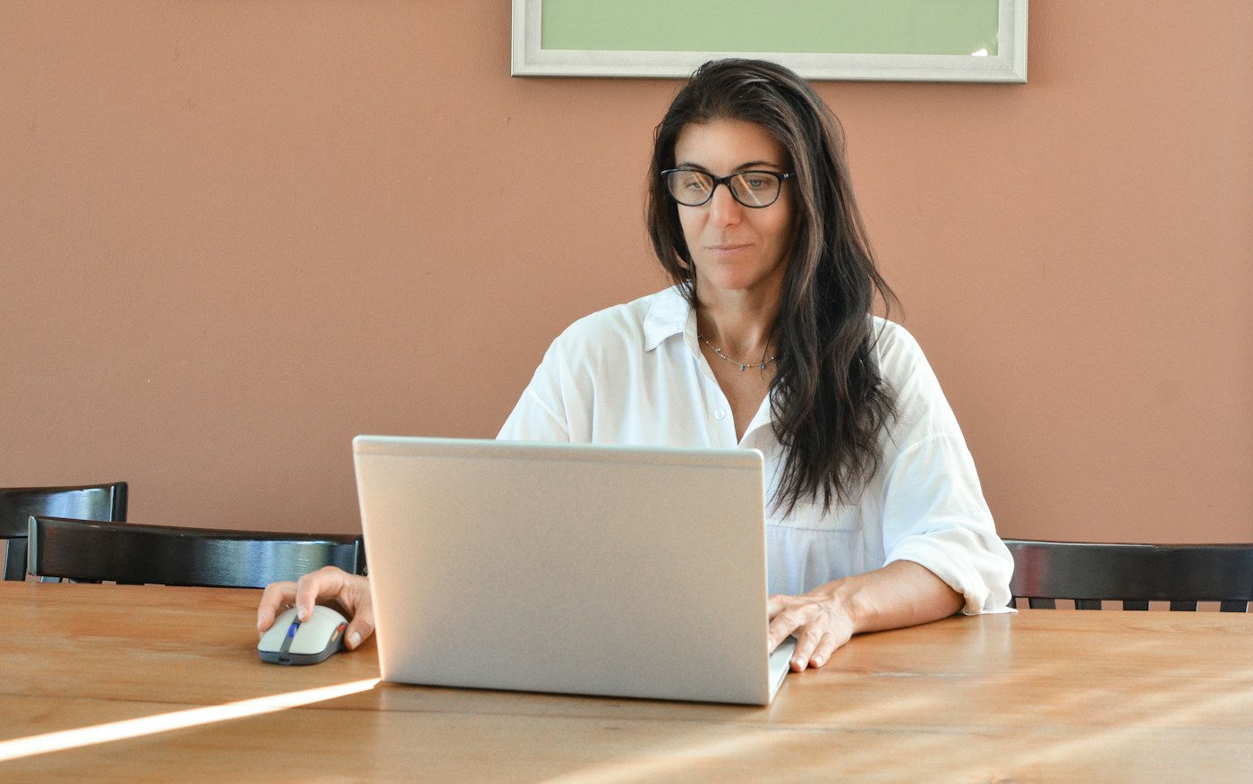A woman working at a laptop at a wooden table