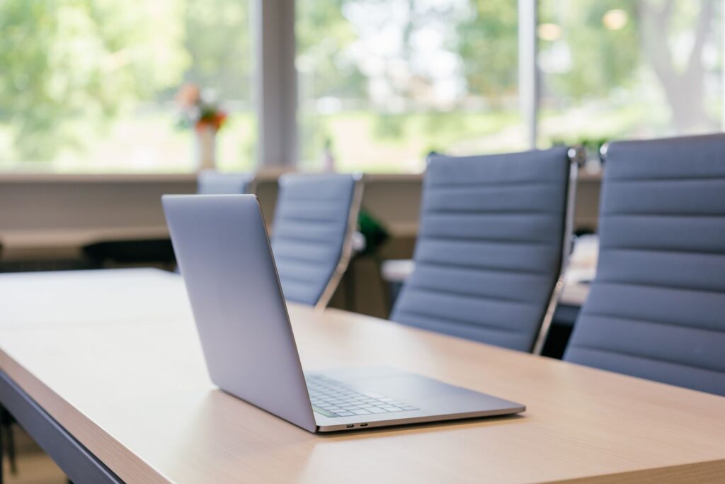A laptop on a meeting-room table in a sunlit office