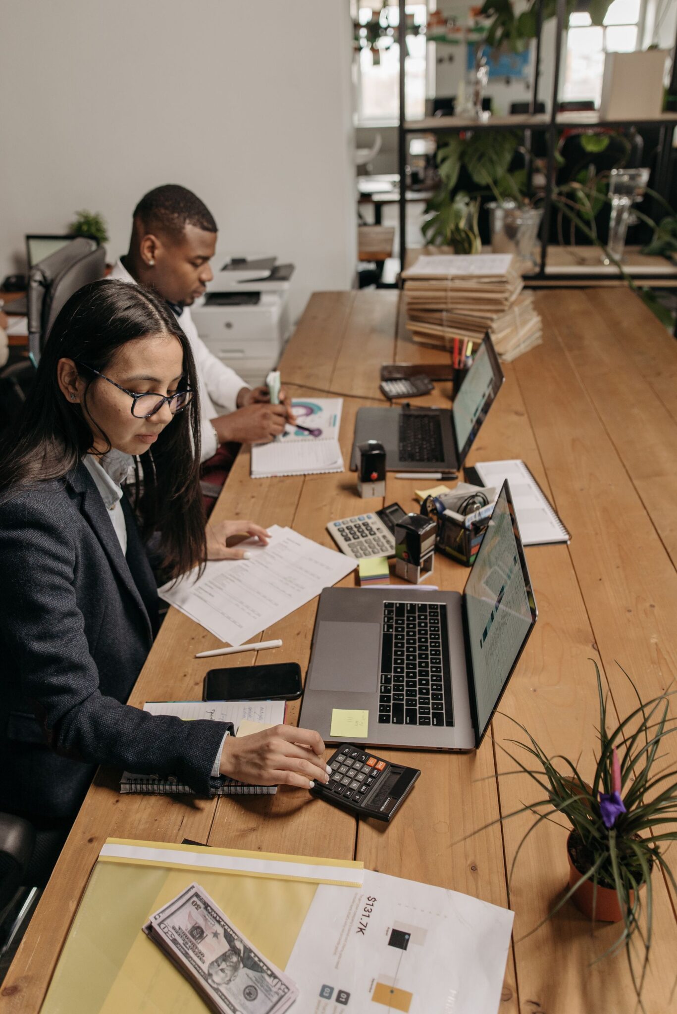 Two accountants working through paperwork and figures together at a shared desk